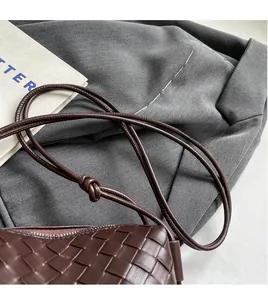 Detailed close-up of dark brown woven leather bag featuring a handcrafted knotted strap
