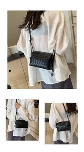 Detail of black woven leather texture on square shoulder bag with knotted strap design