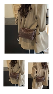 Detailed view of dark brown woven leather crossbody bag with zipper and shoulder strap