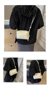 Detailed view of woven beige crossbody bag with wide leather straps and knotted shoulder strap