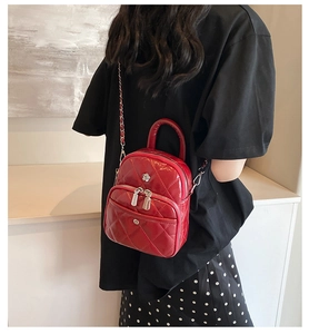 Vue portée d'un petit sac bandoulière rouge matelassé avec chaîne argentée et emblème