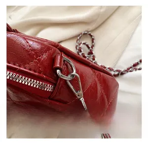 Détail du crochet argenté et de la chaîne sur le sac matelassé bordeaux en cuir