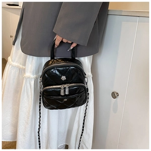 Close-up of black quilted leather mini bag with silver flower charm and chain strap