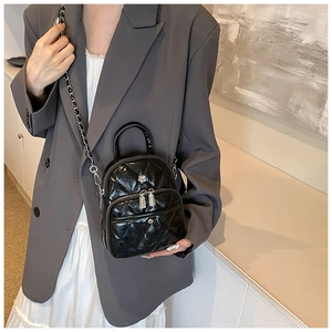 Fashionable black quilted crossbody bag with silver chain strap shown on a model