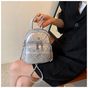 Detail of silver metallic quilted mini bag with floral clasp and chain strap on blazer