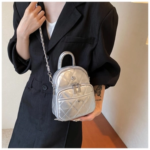 Détail du mini sac argenté matelassé avec chaîne métallique et logo en forme de fleur