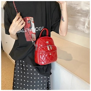 Detail of red quilted patent leather bag with silver floral hardware and chain strap