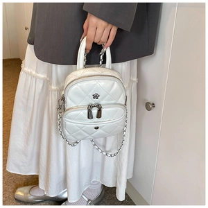 Detail showing white quilted mini bag with silver flower accent and chain strap