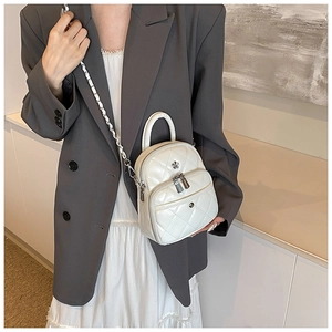 Détail d'un mini sac matelassé blanc avec bandoulière chaîne et fleur en métal