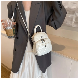 Close-up of white quilted mini bag with floral hardware and silver chain strap details