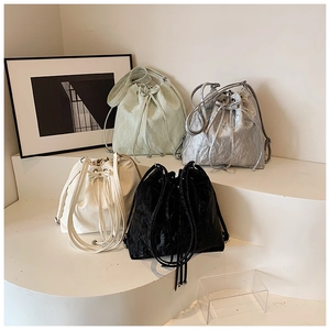 Detailed showcase of drawstring bucket bags in green, white, black and silver textures