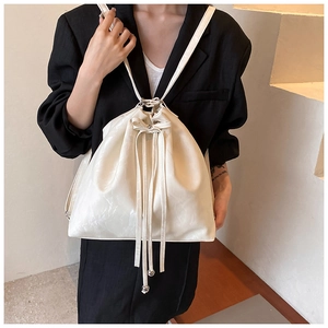 Detail of white drawstring bucket backpack with glossy wrinkled texture and bow accessory