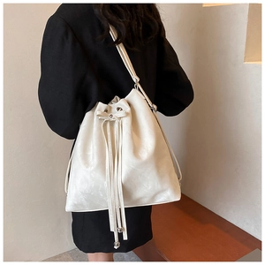 Detailed back view of a large cream drawstring bucket bag worn over a black blazer