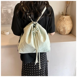 Detail of light green drawstring bucket bag with soft leather texture and bow accent