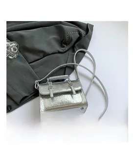 Detail of silver metallic textured messenger bag with pleated leather and round handle