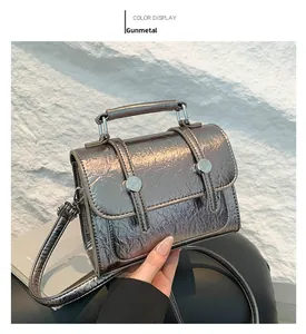 Detail of gunmetal crossbody bag with crinkled metallic finish and silver buckle