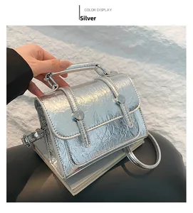 Detail of silver messenger bag featuring cracked metallic texture and metal buckle