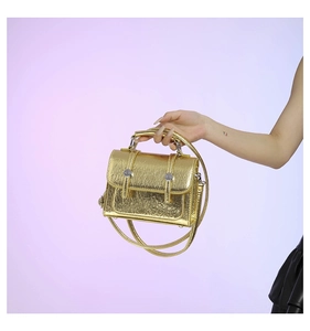 Detail view of metallic gold mini messenger bag with wrinkled texture and handle