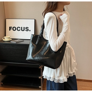 Black large capacity tote bag with glossy finish shown on shoulder