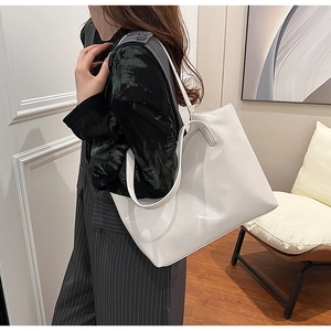 Model wearing a minimalist large capacity white underarm tote bag in an indoor setting