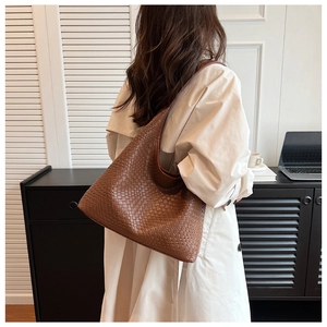 Brown woven leather hobo shoulder bag with checkered texture shown on model in a casual setting