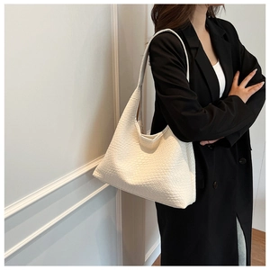 Detailed view of cream woven hobo bag with checkerboard texture on female model shoulder