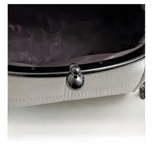 Detail shot of the white lychee grain leather shell bag with metal kiss-lock closure