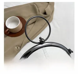Detail of white lychee leather bag featuring a round black metal handle and topstitching