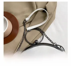 Detail of white quilted handbag with round metal handle and elegant chain strap