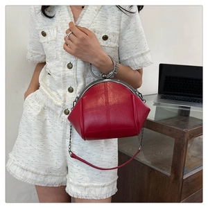 Detail of red shell-shaped bag with silver ring handle and metal chain strap