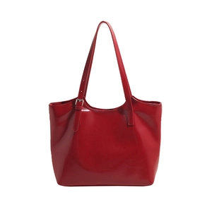 Front view of a glossy red leather tote bag with adjustable shoulder strap and buckle