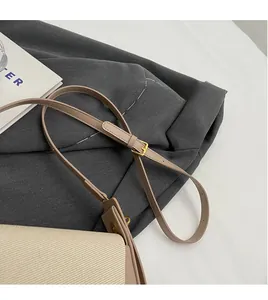 Détail de la bandoulière réglable en cuir et boucle dorée sur un sac beige chic