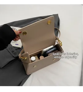 Vue détaillée de l'intérieur spacieux du sac à main en cuir beige avec boucles dorées