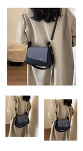 Détail du rabat tissé bleu-gris et lettrage doré sur un sac bandoulière rétro