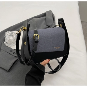 Detail of grey twill and black leather crossbody bag with elegant gold hardware