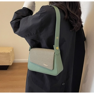 Détail du sac bandoulière vert Morandi avec boucles dorées et logo porté par un mannequin