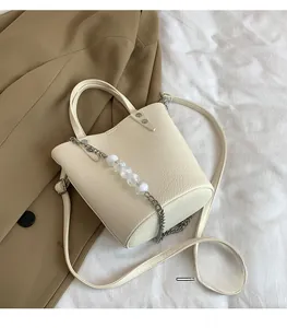 Macro detail of cream white pebbled leather texture with silver chain and bead accents