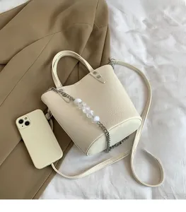 Detail of off-white lychee grain leather bucket bag with silver beaded chain decoration