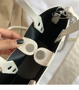 Detail view of silver magnetic closure and black lining on cream pebble leather bag