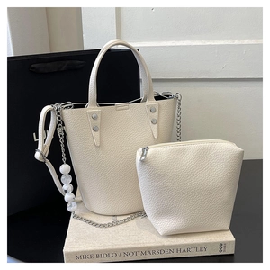 Detail of white lychee texture bucket bag set with decorative pearl chain and rivets