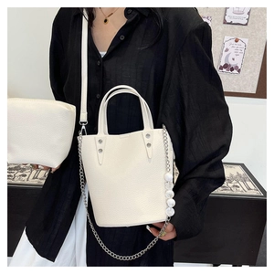 Detailed shot of white lychee leather bucket bag with silver studs and pearl chain strap
