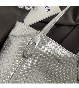 Detail of silver woven leather tote bag showing manual stitching and texture