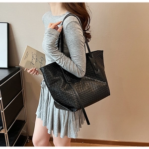 Detail of black woven tote bag showing large capacity and textured faux leather finish