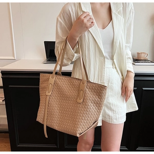 Detail of a khaki woven leather tote bag with Intrecciato pattern for daily commuting