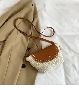 Detail of woven straw crossbody bag with brown leather flap and golden rivet studs