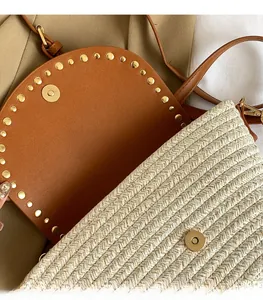Detail of woven straw bag with brown leather flap, gold rivets and metal magnetic closure