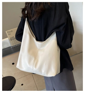 Detail of white leather tote bag with pleated texture shown on model for shoulder fit