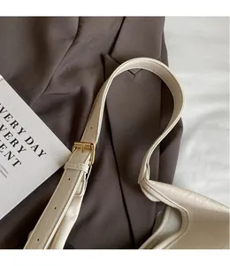 Close-up of adjustable strap with gold metal buckle on a beige leather tote bag