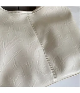 Close-up of off-white tote bag fabric showing wrinkled texture and precise stitching