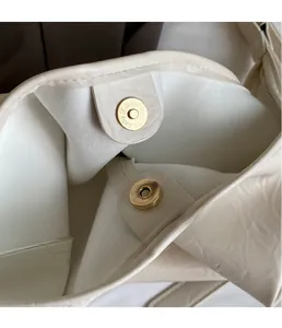 Detail of premium gold magnetic clasp and fine stitching on ivory pebbled leather bag